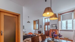 A modern living room with a wooden dining table, a sofa, and a coffee table. There are two pendant lights above the table. - Rua 5 de Outubro by Interhome (Lagos)