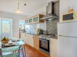 A modern kitchen with a gas stove, oven, microwave, and a dining area with a table and chairs.