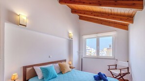 A bedroom with a bed, a nightstand, a lamp, a window with a view, and a wooden ceiling. - Rua 5 de Outubro by Interhome (Lagos)
