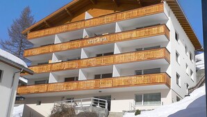 Un edificio de varios pisos con balcones de madera y el nombre "VISCARIA" en la fachada.