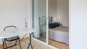 Una habitación con una cama, una mesita con un florero y una silla.