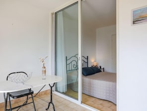 Ein Zimmer mit einem Bett, einem kleinen Tisch mit einer Vase und einem Stuhl.