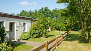 A white building with a wooden fence, surrounded by greenery and trees. - Windrad by Interhome (Norddeich)