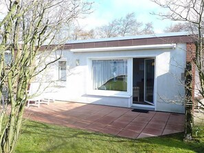 A modern single-story house with a patio, a sliding glass door, and a small garden area. - Windrad by Interhome (Norddeich)