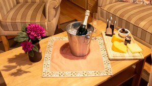 A wooden table with a metal bucket containing a bottle of champagne, a glass, and a cheese board with various cheeses and a jar of jam. - Windrad by Interhome (Norddeich)