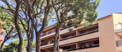 A multi-story building with balconies, surrounded by trees.