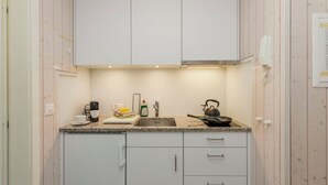 A compact kitchen with white cabinets, a stainless steel sink, a kettle, and a coffee maker. - Suzanne Nr. 21 by Interhome (Schönried)