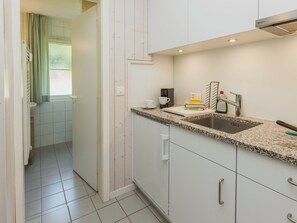 Una cocina compacta con un lavamanos integrado, una cafetera y un escurreplatos.
