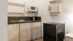 A compact kitchen with a built-in microwave, a coffee maker, and a refrigerator. - Casa Isza (Playa del Carmen)