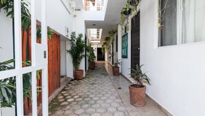 A narrow corridor with potted plants, white walls, and a tiled floor. - Casa Isza (Playa del Carmen)
