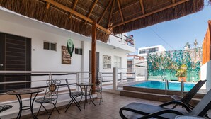 A covered outdoor area with lounge chairs and tables, a pool, and a building with a sign that says "It's how I love you." - Casa Isza (Playa del Carmen)