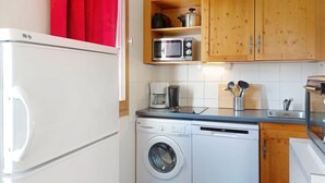 A compact kitchen with a washing machine, a microwave, and a coffee maker. - Les erables by Interhome (Saint Gervais)