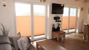 Een woonkamer met een bank, salontafel en een aan de muur bevestigde televisie.