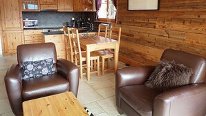 Een gezellige woonkamer met leren banken, een houten salontafel, en een eethoek met houten stoelen en een tafel.