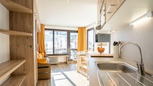 A modern kitchen with a stainless steel sink, wooden shelves, and a view of the city through large windows. - Les Tufs (Val Claret) by Interhome (Tignes)