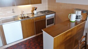 Una cucina compatta con mobili in legno, un lavello, un fornello e una macchina per il caffè.