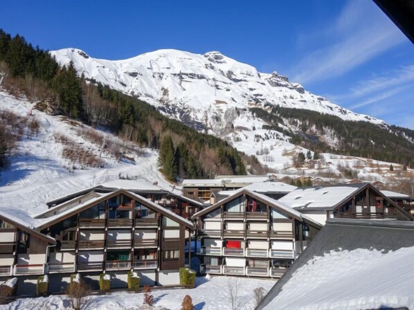 A mountain lodge with multiple chalet-style buildings, snow-covered roofs, and a backdrop of a snow-capped mountain.
