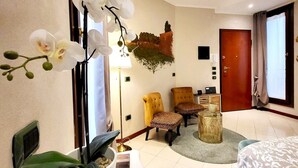 A hotel room with a bed, two chairs, a small table, a potted plant, and a wall-mounted artwork. - A stone's throw from the Castle (Ferrara)