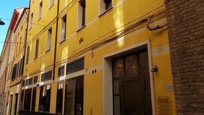 A yellow building with multiple windows and a door. - A stone's throw from the Castle (Ferrara)