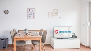 En moderne stue med et spisebord, stole, et fjernsyn og billeder i rammer på væggen.
