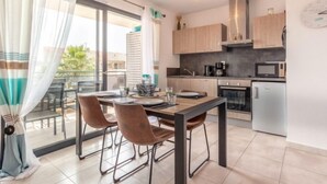 Una cocina moderna con zona de comedor, que cuenta con un ventanal con cortinas, una estufa empotrada y un microondas.