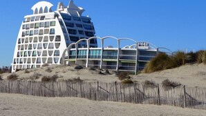 A modern hotel with a unique architectural design, featuring multiple balconies and a prominent dome structure. - Poséidon by Interhome (La Grande Motte)