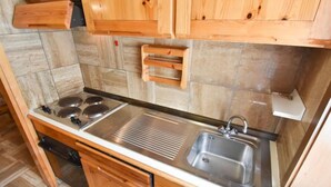 Une cuisine dotée de meubles en bois, d’un évier en acier inoxydable et d’un four double.