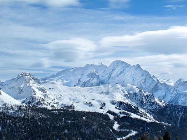 A mountainous landscape with snow-covered peaks and a forested valley. - Fontanelle by Interhome (Canazei)