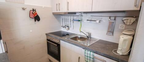 A compact kitchen with a sink, stove, and cabinets.