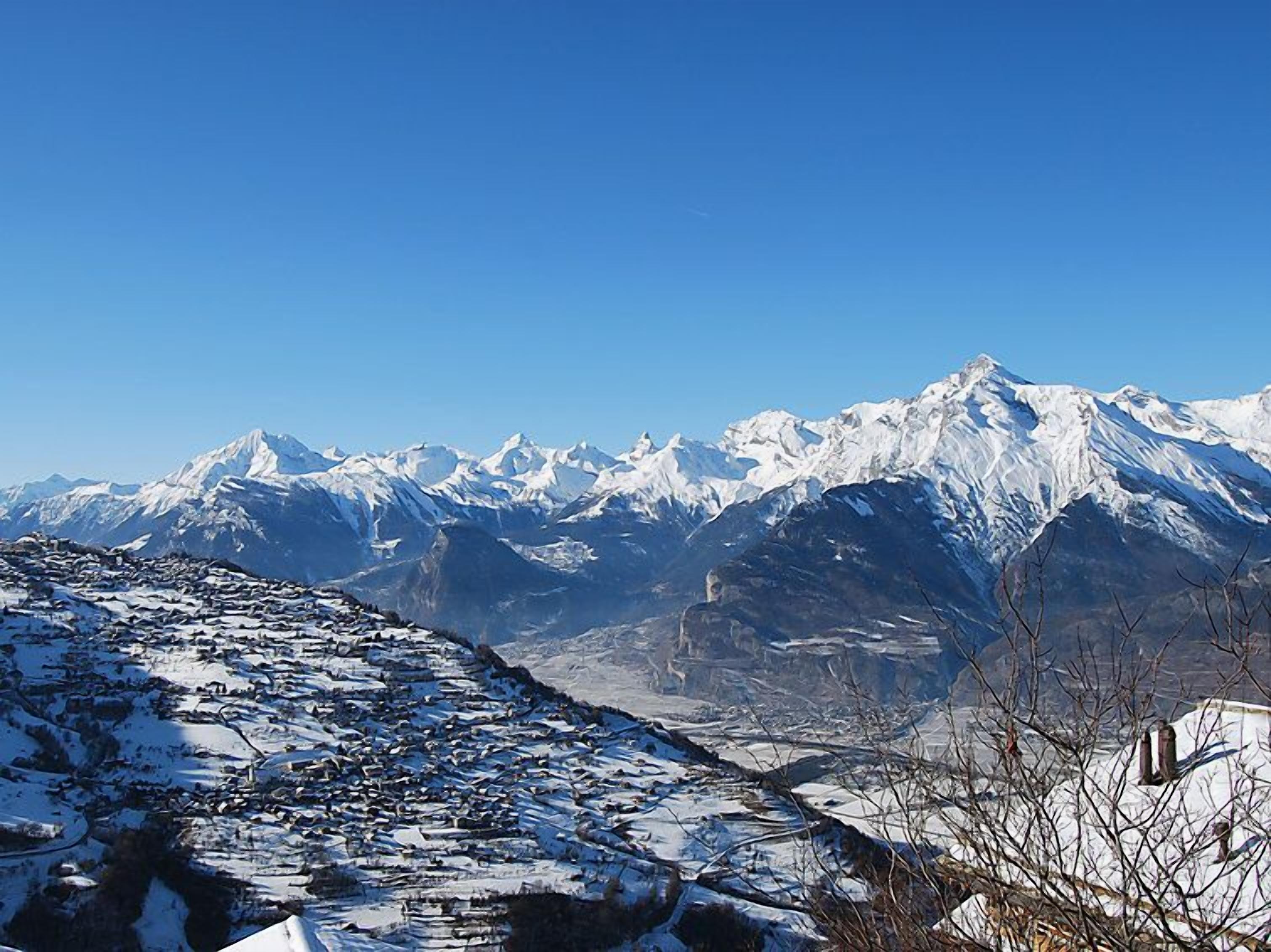 Une chaîne de montagnes enneigée sous un ciel dégagé.