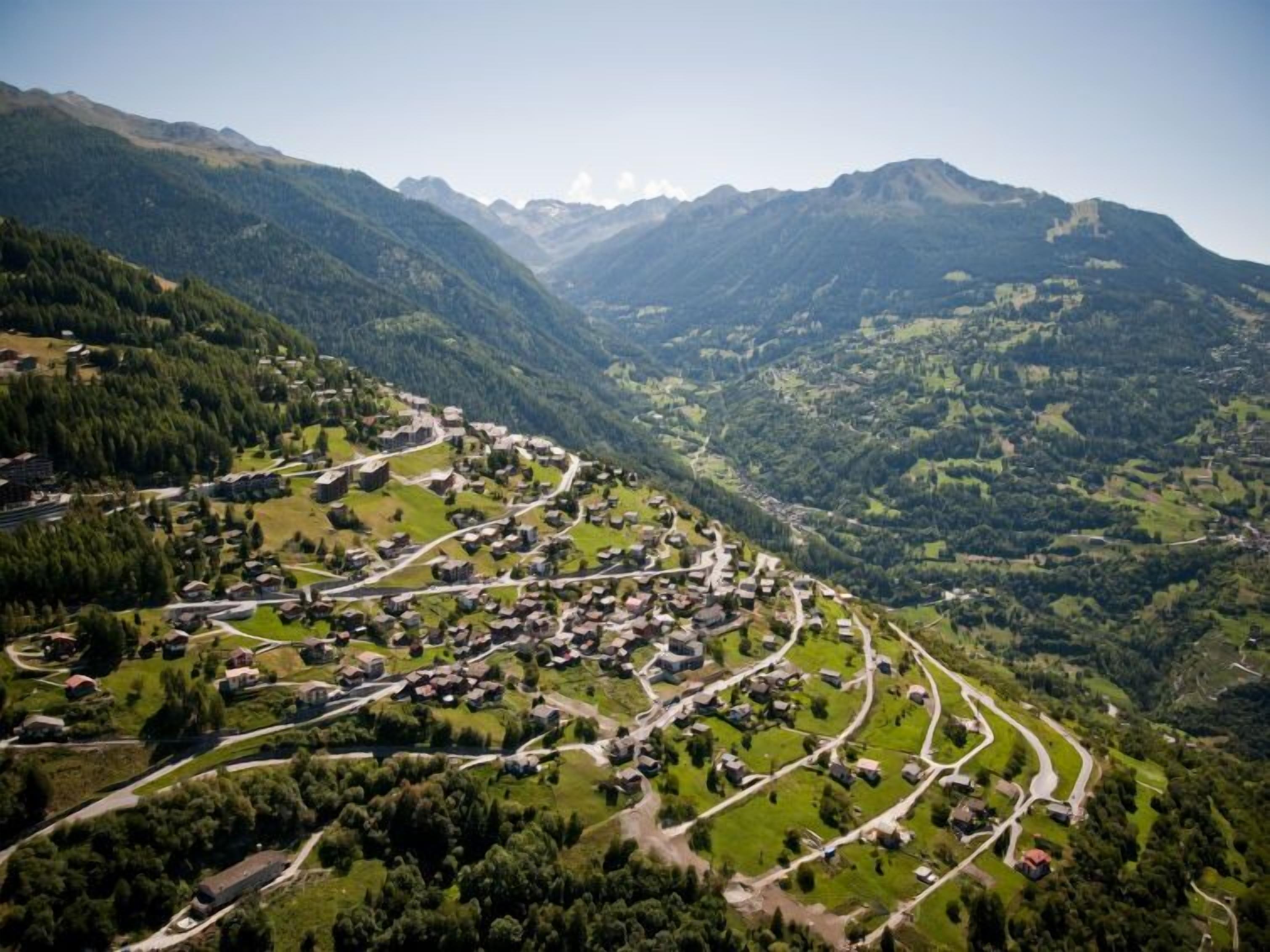 A mountainous village with winding roads and houses.