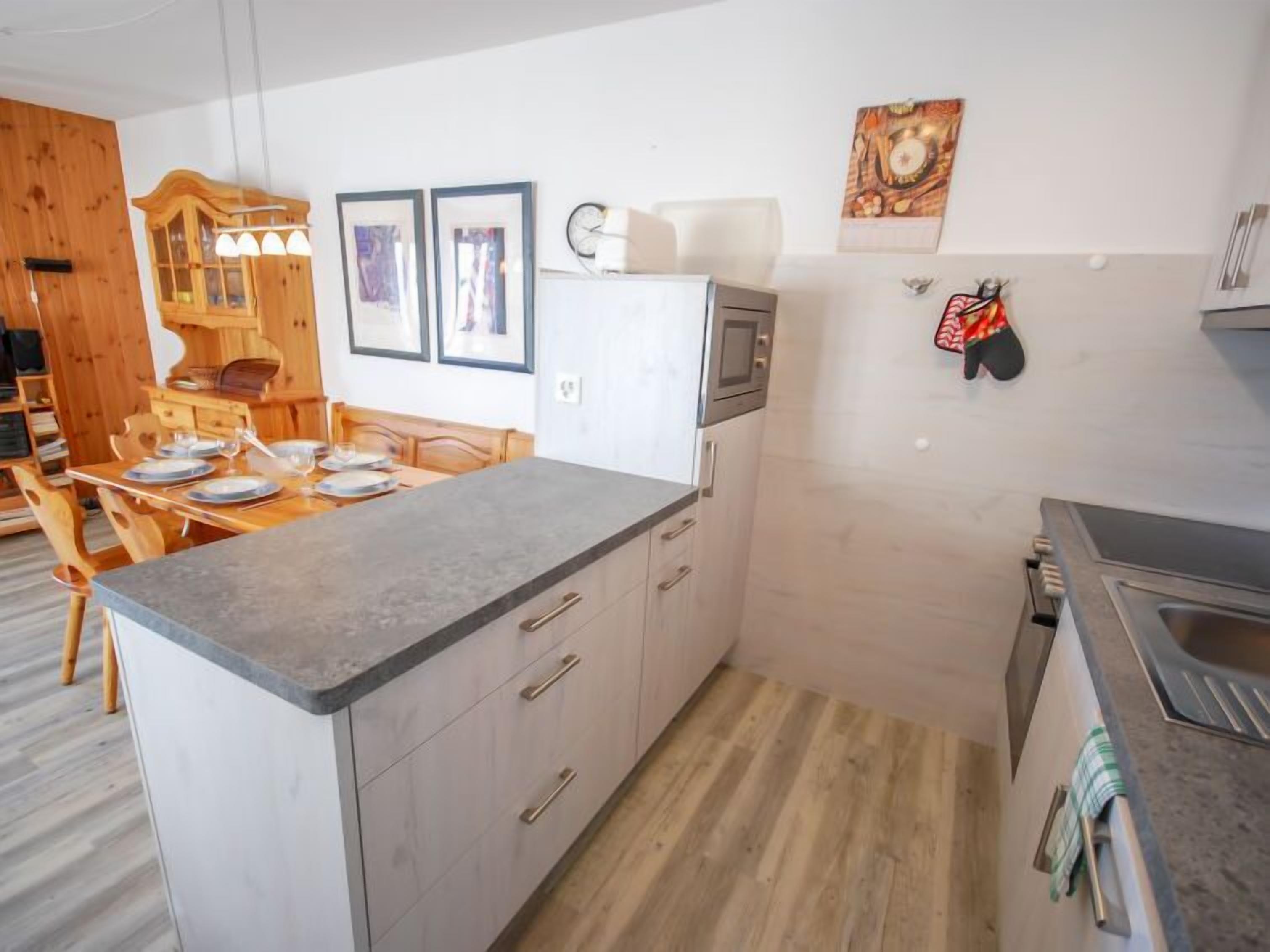 Une cuisine moderne dotée d’un îlot central, d’une table à manger en bois et d’un four à micro-ondes.