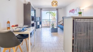 Een moderne woonkamer met een eethoek, een bank, een televisie en een balkon met uitzicht.