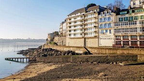 Un hôtel situé sur la côte, avec plusieurs étages, des balcons et un restaurant au rez-de-chaussée.