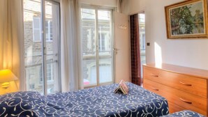 Une chambre à coucher avec un lit, une commode et un tableau accroché au mur.