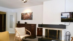 Un saló amb una xemeneia, una televisió penjada a la paret i un quadre sobre la xemeneia.