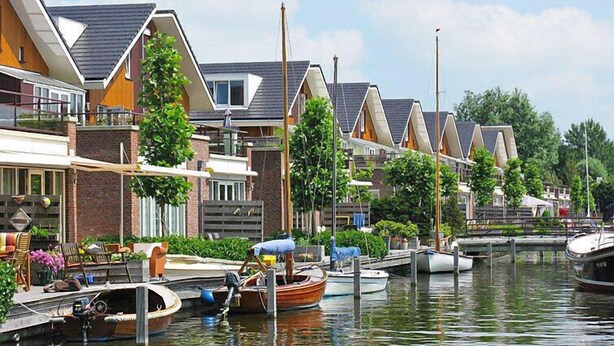 A canal-side residential area with houses, a dock with boats, and a clear sky. - Westergeest by Interhome (Uitgeest)