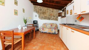 A compact kitchen with a stone wall, wooden furniture, and a tiled floor. - Cerbiatto n°5A by Interhome (Gaiole in Chianti)