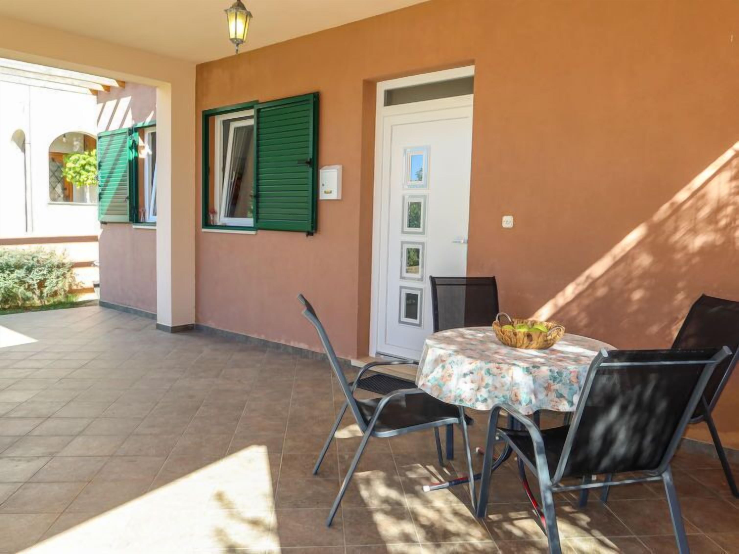 An outdoor patio area with a table and chairs, a door, and a wall with shutters.