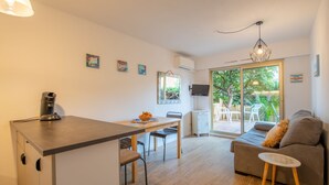 Une cuisine moderne avec un coin repas, un canapé et une petite table. On trouve une machine à café sur le plan de travail et un téléviseur fixé au mur.