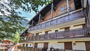 A multi-story building with balconies, a paved driveway, and a grassy area. - Apartment Apt 41 by Interhome (Canazei)