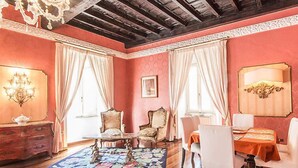 Une pièce avec un plafond en bois, un lustre, une table à manger avec des chaises, un canapé et un tapis décoratif.