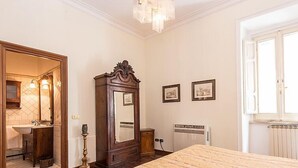 Une chambre à coucher comprenant un lit, une commode, un miroir, un radiateur et une fenêtre.