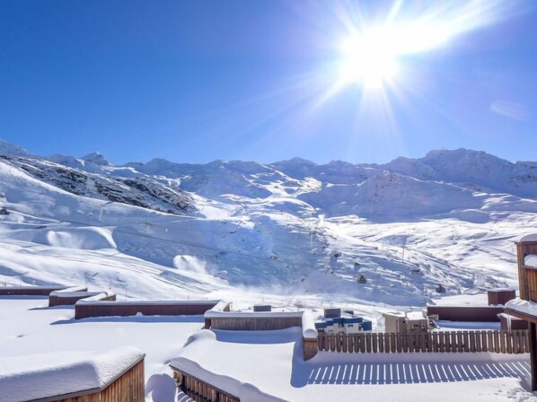 A snow-covered mountain landscape with a clear sky and a bright sun.