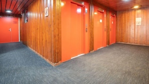 A hallway with wooden paneling and orange doors, likely leading to rooms or other areas. - Sérac A10 by Interhome (Val Thorens)