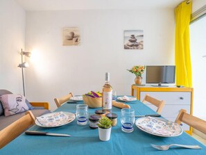 Un comedor con una mesa dispuesta para cuatro, un televisor y obras de arte en las paredes.