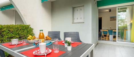 Een eetgedeelte met een tafel voor twee personen, compleet met borden, bestek en een fles sap.