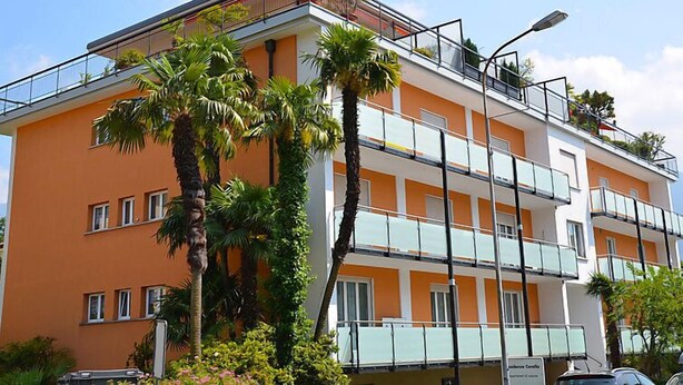 A multi-story hotel with balconies, palm trees, and a clear sky. - Residenza Corallo by Interhome (Ascona)
