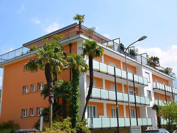 A multi-story building with balconies, palm trees, and a clear sky.