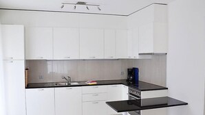 Una cuina moderna amb armaris blancs, tauleig negre i forn encastrat.